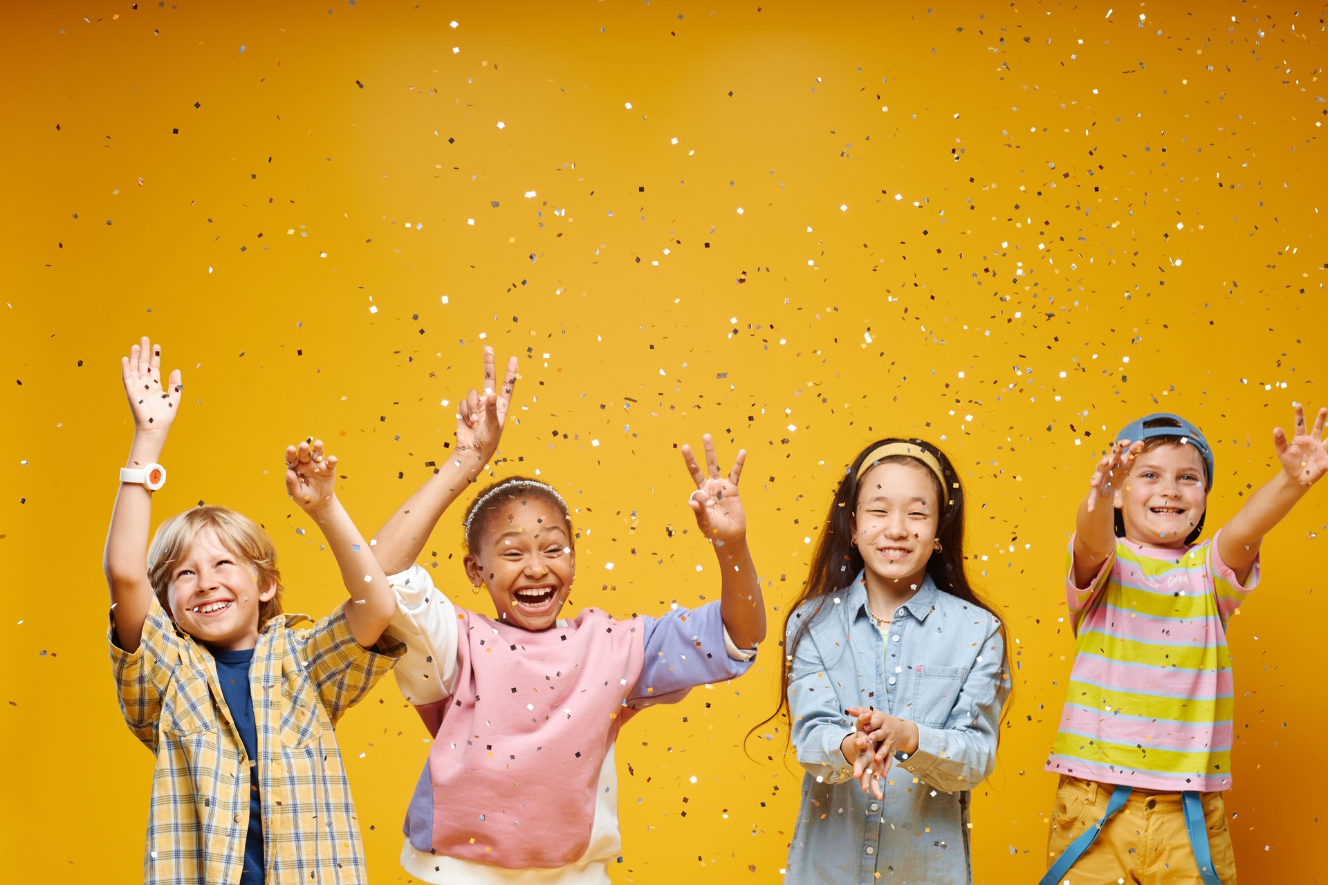 Diverse Group of Four Preteen Kids Catching Confetti in Orange Studio